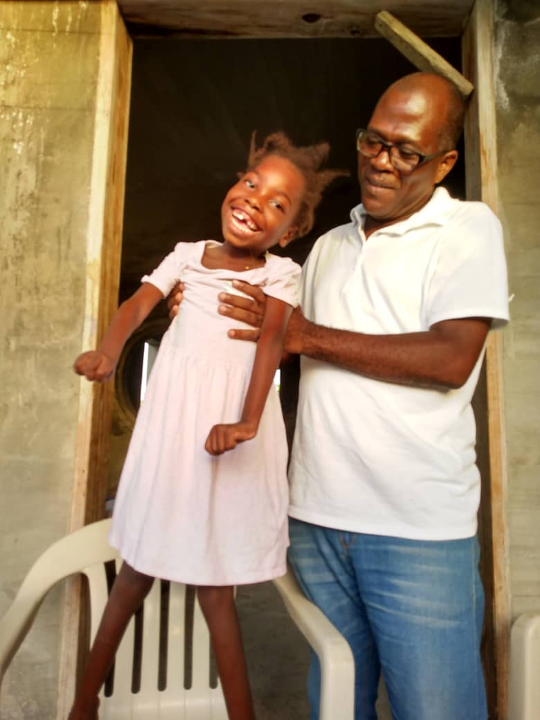 A caregiver lovingly supporting a young girl with a disability in Haiti.