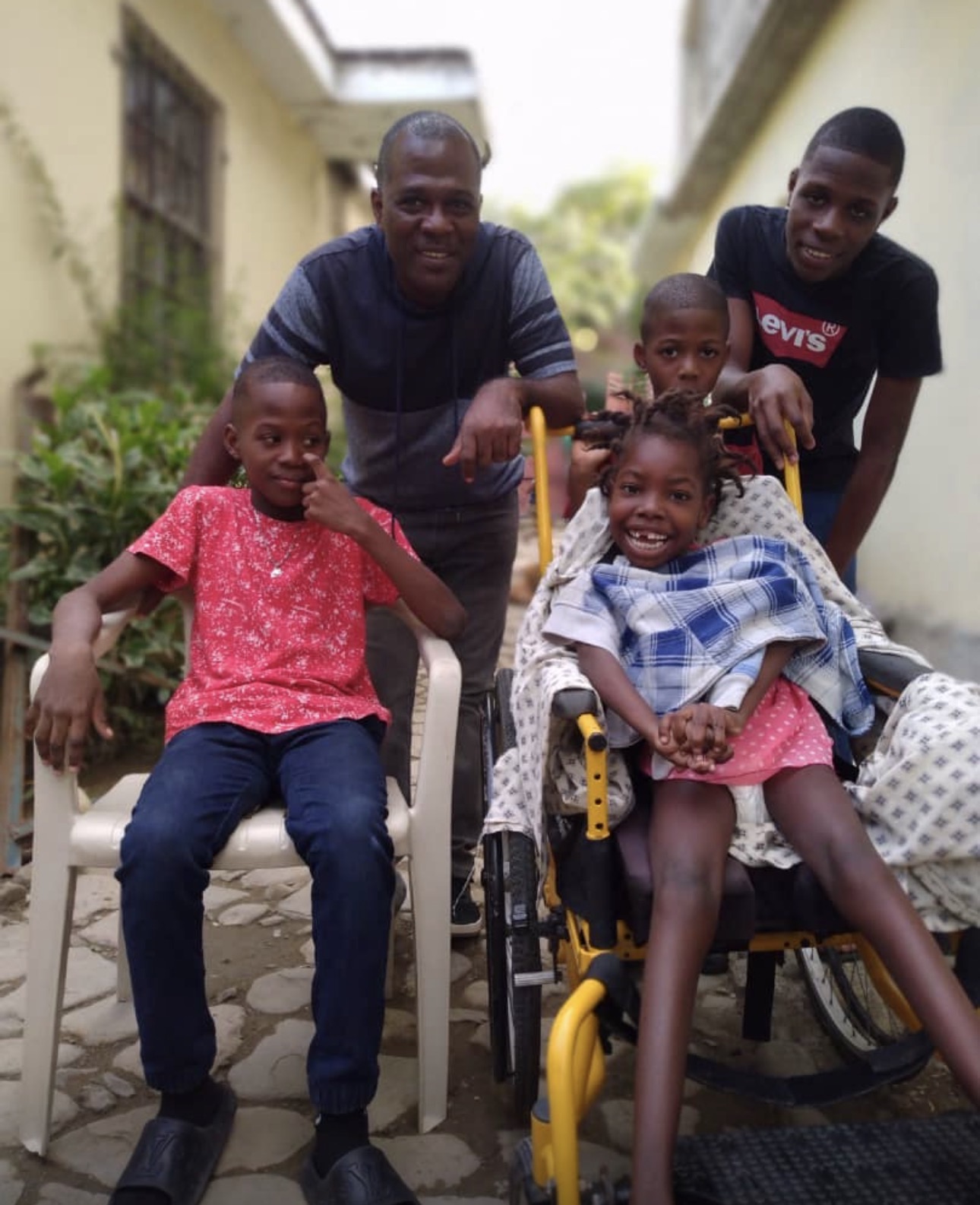 A Christian family gathered around a young girl with a disability in her wheelchair.